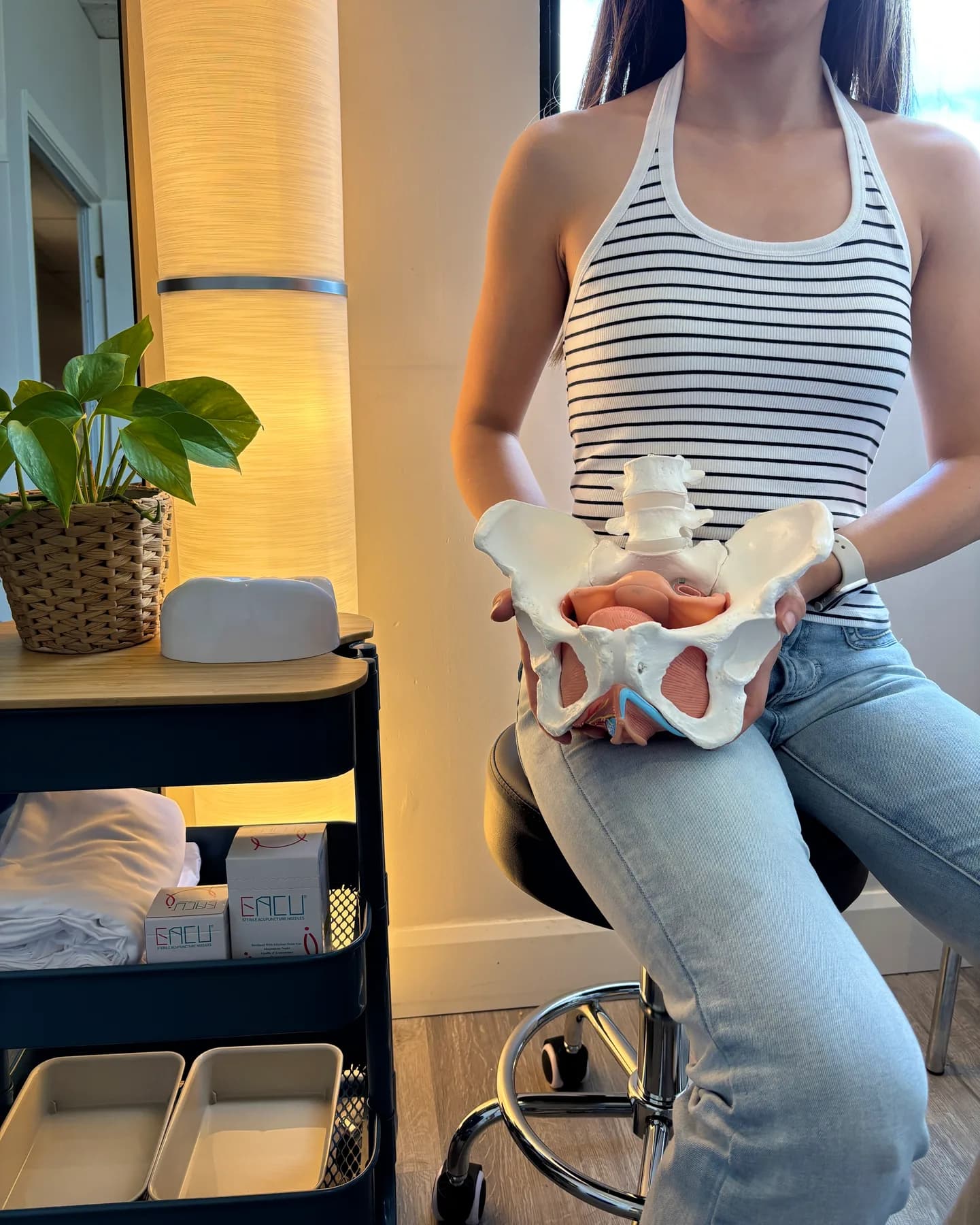 Physiotherapist holding a pelvic anatomy model during a pelvic health consultation
